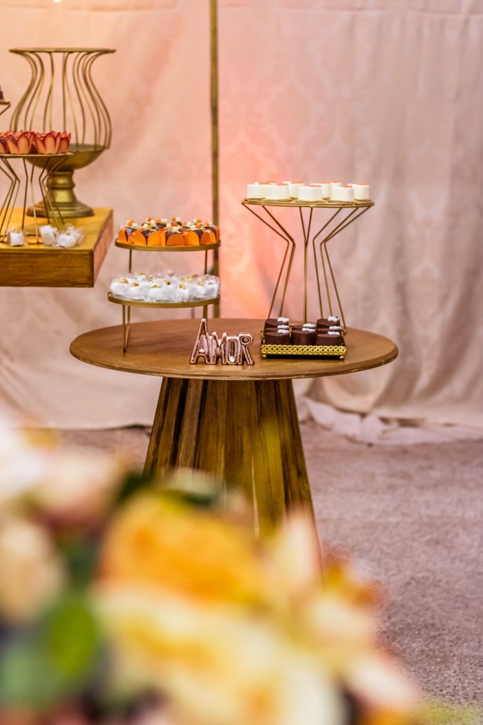 Stylish dessert table setup with decorative cakes and 'Amor' sign, perfect for weddings or events.